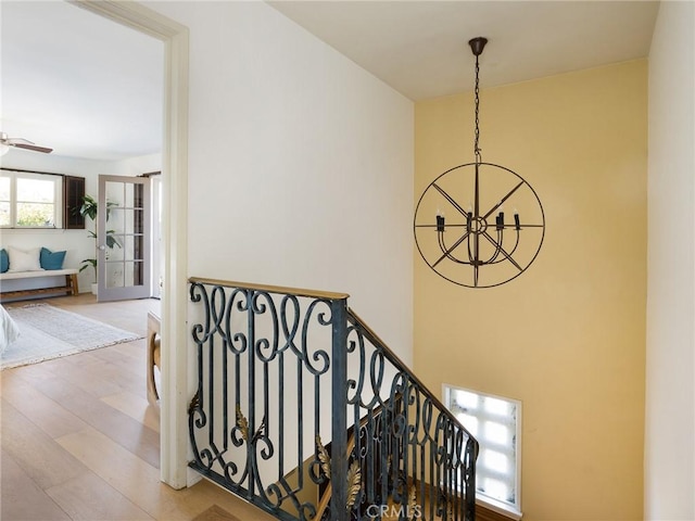 stairway featuring wood-type flooring and ceiling fan with notable chandelier