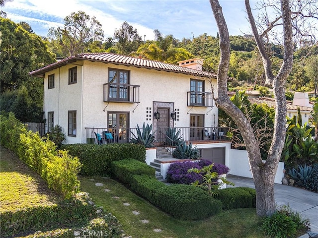 mediterranean / spanish-style home featuring a garage and a balcony