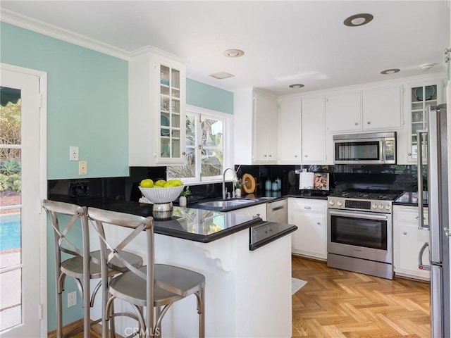 kitchen with white cabinetry, sink, light parquet floors, kitchen peninsula, and stainless steel appliances