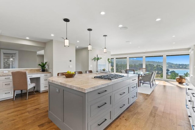 kitchen featuring decorative light fixtures, light wood-type flooring, stainless steel gas cooktop, and a kitchen island