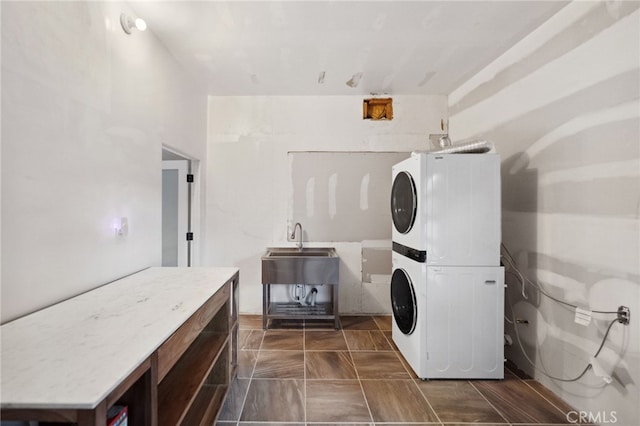 washroom with stacked washing maching and dryer and sink