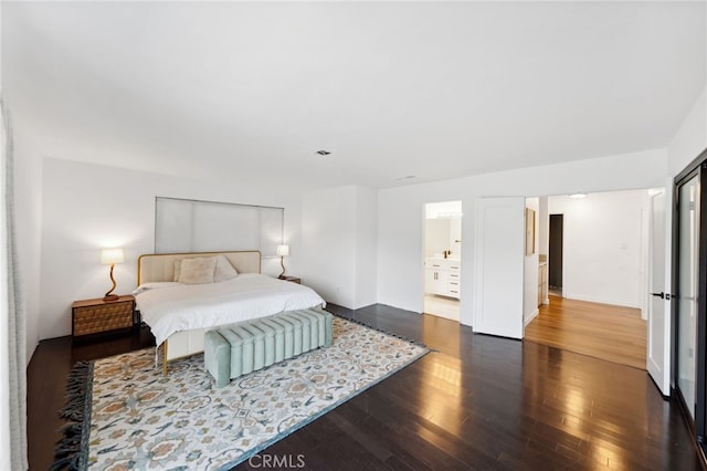 bedroom featuring ensuite bathroom and dark hardwood / wood-style flooring