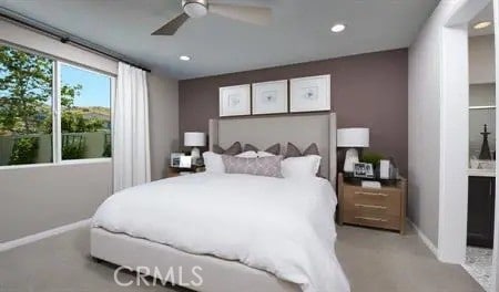 carpeted bedroom with ceiling fan and ensuite bath