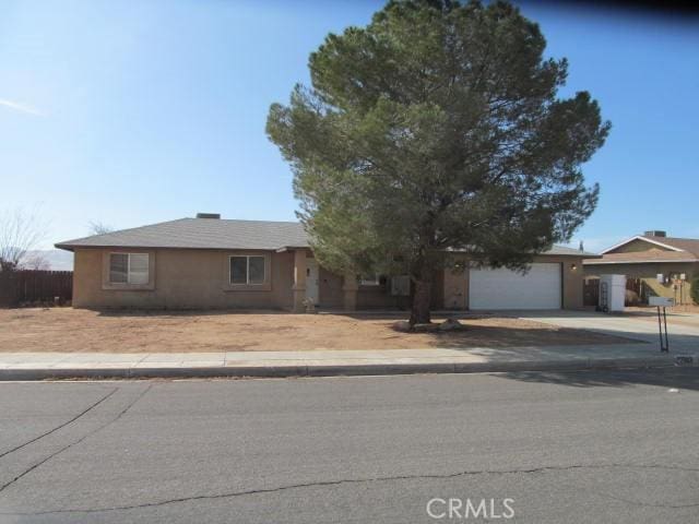 single story home featuring driveway, an attached garage, and stucco siding