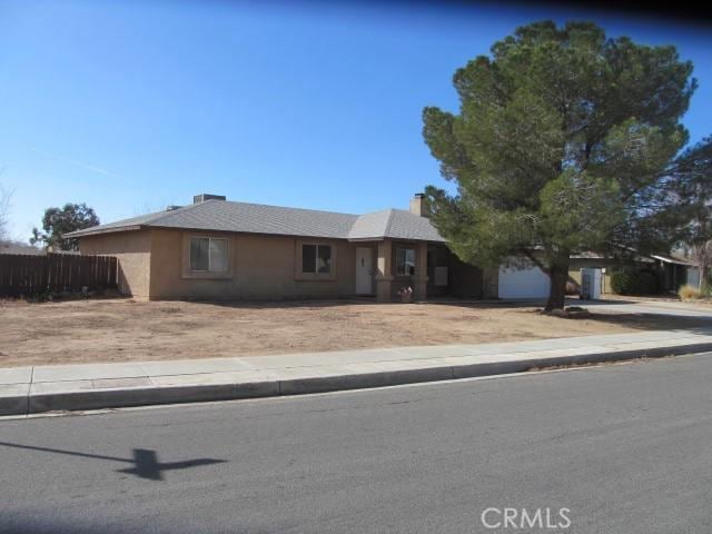 ranch-style home with driveway, an attached garage, and fence