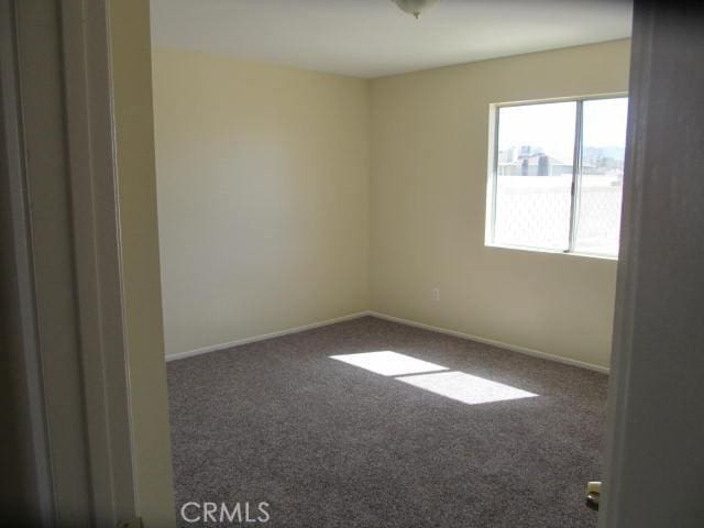 empty room featuring carpet floors and baseboards