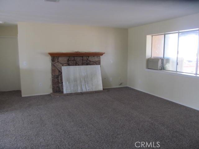 unfurnished living room with carpet floors and a stone fireplace