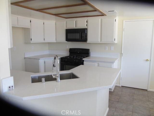 kitchen with light countertops, white cabinetry, a sink, and black appliances