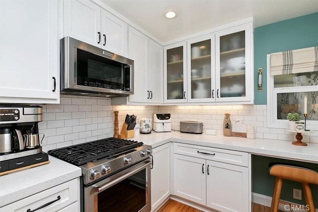 kitchen with stainless steel appliances, white cabinetry, and decorative backsplash