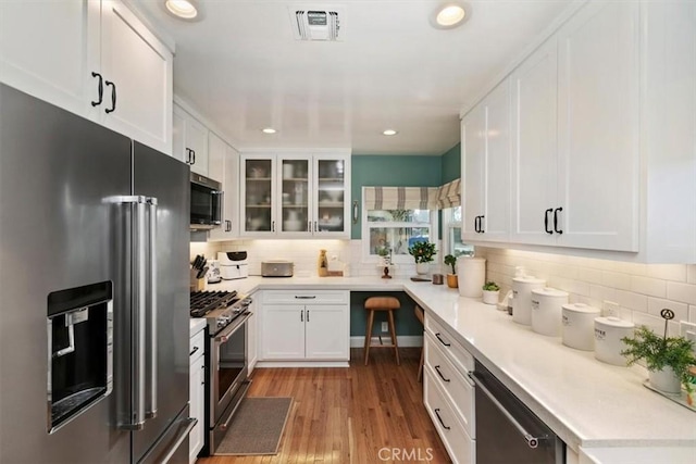 kitchen featuring white cabinetry, light wood-type flooring, backsplash, and premium appliances