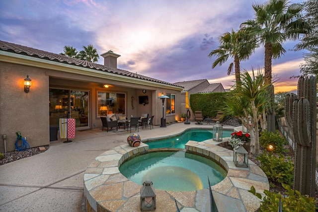 pool at dusk with an in ground hot tub and a patio area