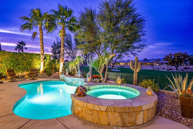 pool at dusk featuring an in ground hot tub