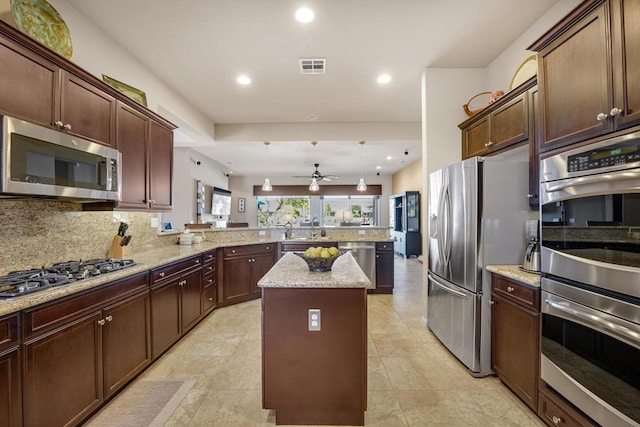 kitchen featuring appliances with stainless steel finishes, kitchen peninsula, a kitchen island, pendant lighting, and decorative backsplash