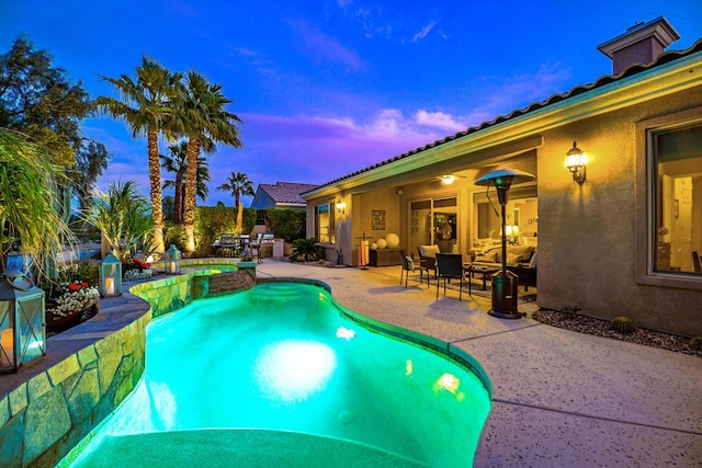 pool at dusk featuring an in ground hot tub and a patio area