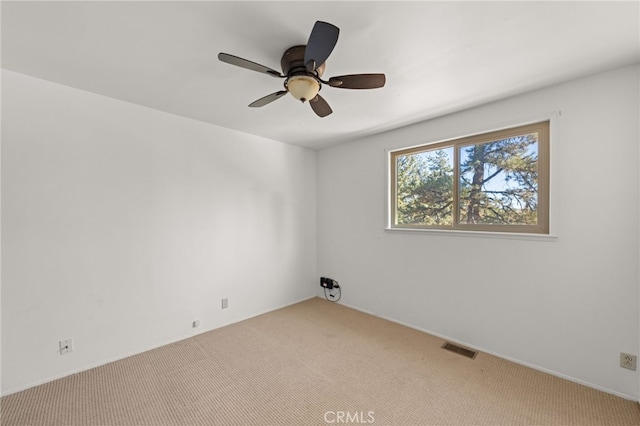 spare room with visible vents, a ceiling fan, and light colored carpet