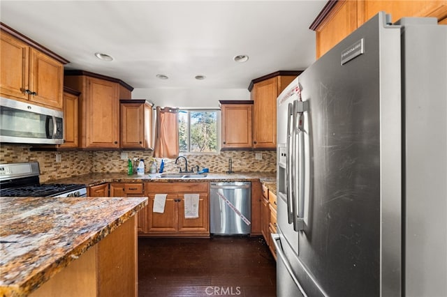 kitchen with stainless steel appliances, decorative backsplash, a sink, and brown cabinets