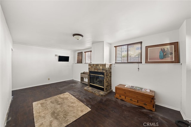 living room featuring baseboards, wood finished floors, and a glass covered fireplace