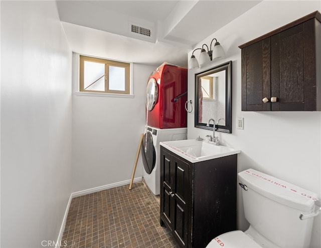 bathroom featuring stacked washer / drying machine, visible vents, toilet, vanity, and baseboards