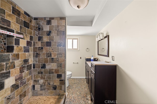 bathroom with vanity, toilet, and a tile shower