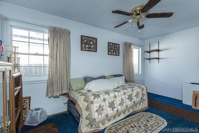 carpeted bedroom featuring multiple windows and ceiling fan