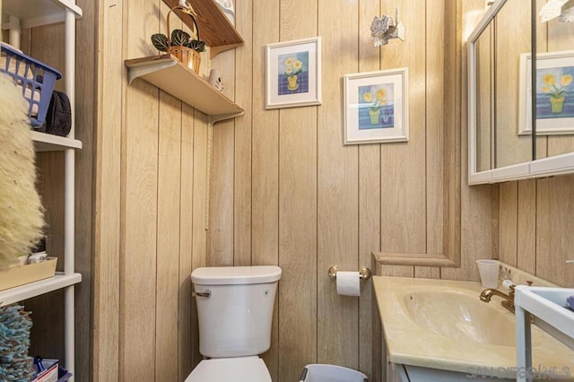 bathroom featuring wooden walls, vanity, and toilet