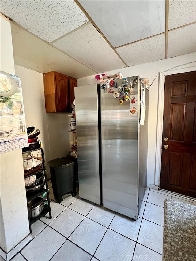 kitchen featuring a paneled ceiling, stainless steel fridge, and light tile patterned floors