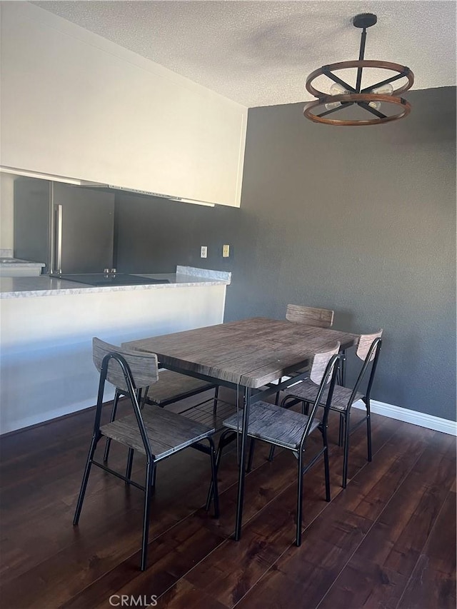 dining area featuring dark wood-type flooring and a textured ceiling