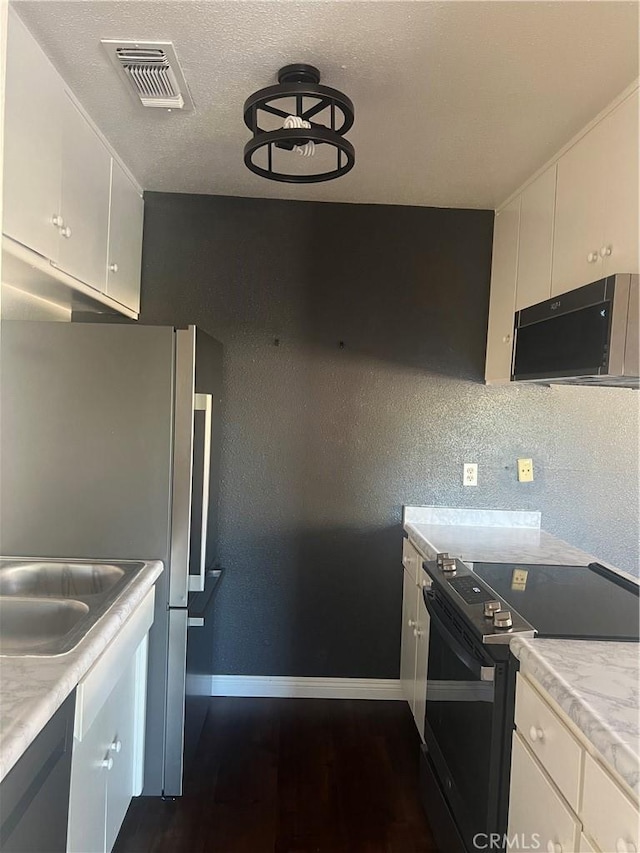 kitchen with white cabinetry, dark wood-type flooring, black appliances, and a textured ceiling