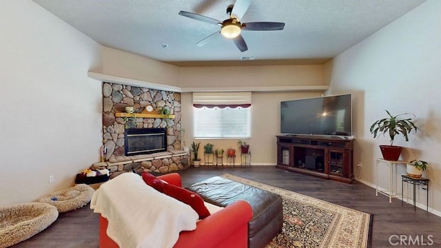 living room featuring dark wood-type flooring, ceiling fan, and a fireplace