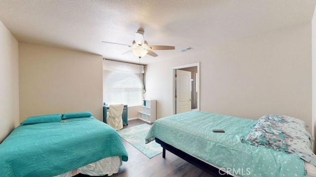 bedroom featuring wood-type flooring, a textured ceiling, and ceiling fan