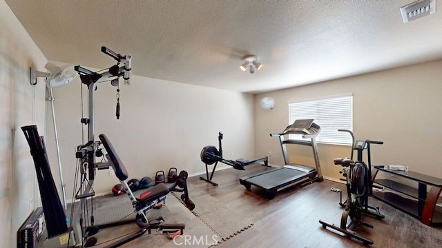 workout room with wood-type flooring and a textured ceiling