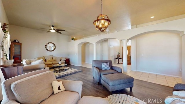 living room with decorative columns, dark wood-type flooring, and ceiling fan