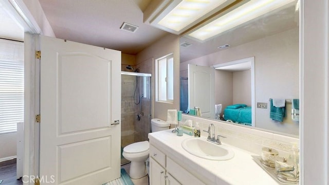 bathroom with vanity, toilet, a shower with door, and plenty of natural light