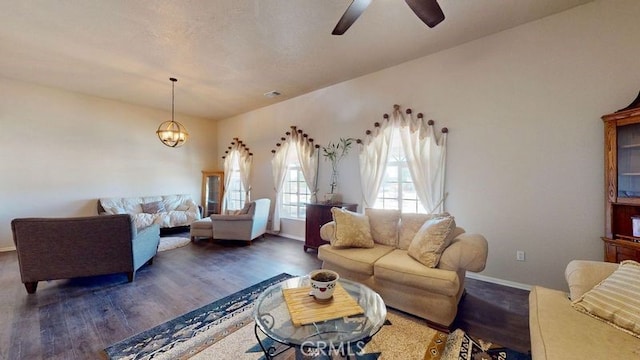 living room with ceiling fan with notable chandelier and dark hardwood / wood-style floors