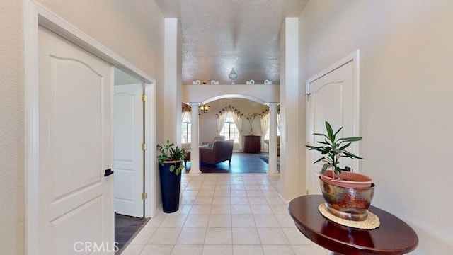 hall featuring light tile patterned floors and decorative columns