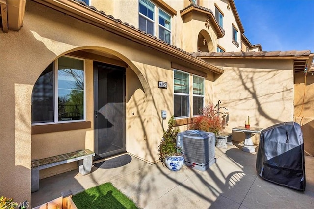 entrance to property with cooling unit and a patio