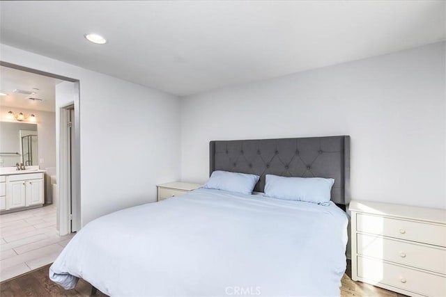 bedroom with sink, light hardwood / wood-style flooring, and ensuite bathroom