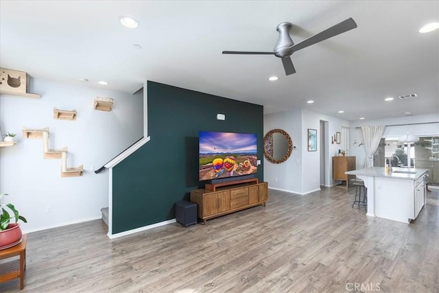 living room with sink, hardwood / wood-style flooring, and ceiling fan