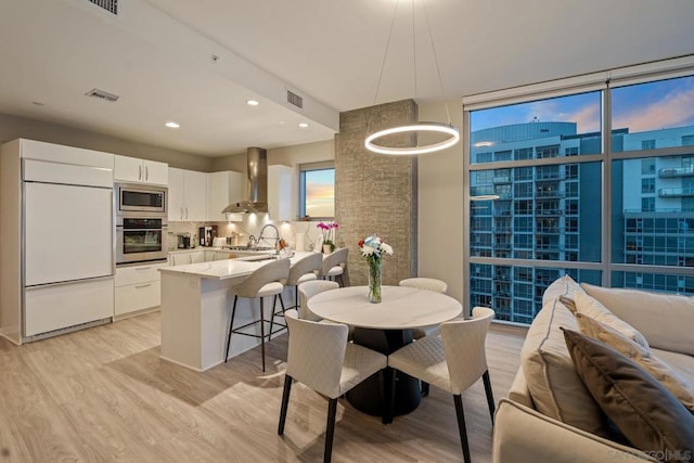 dining space featuring floor to ceiling windows, sink, and light hardwood / wood-style floors