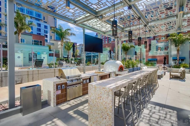 view of patio with area for grilling, a grill, and exterior bar