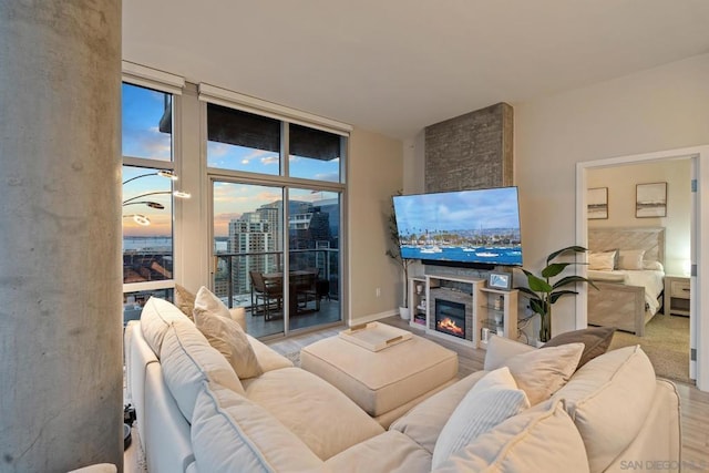 living room featuring floor to ceiling windows, a stone fireplace, and light hardwood / wood-style floors