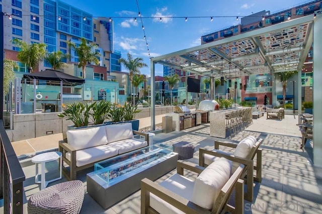 view of patio with exterior bar, exterior kitchen, and an outdoor living space with a fire pit