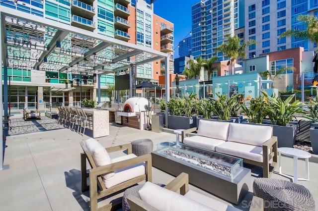 view of patio / terrace featuring a pergola, an outdoor living space with a fire pit, and an outdoor bar