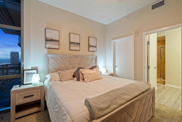 bedroom with ensuite bath and light wood-type flooring