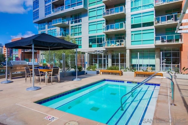 view of pool featuring area for grilling and a patio area