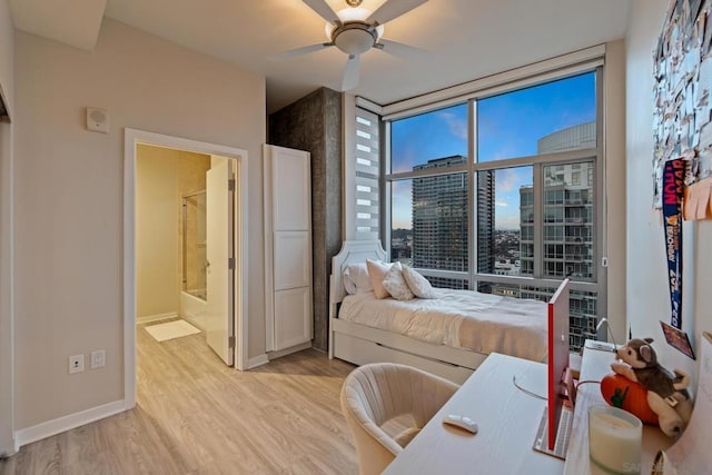 bedroom with light hardwood / wood-style flooring, expansive windows, ceiling fan, and ensuite bathroom