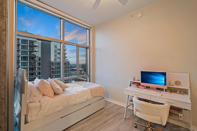 bedroom featuring a wall of windows, ceiling fan, and light wood-type flooring