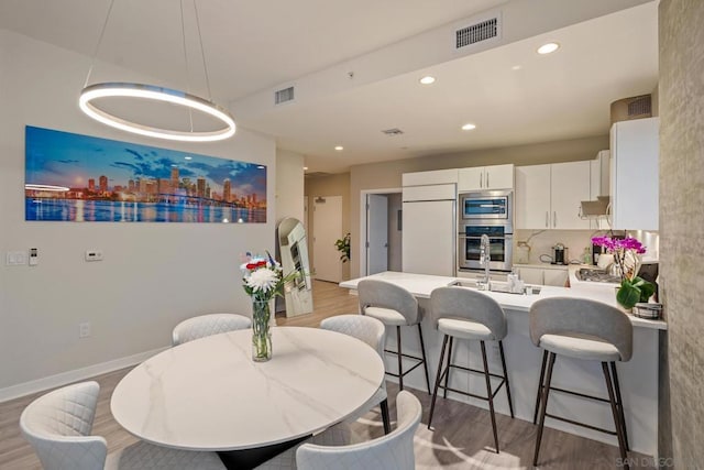 kitchen featuring stainless steel microwave, tasteful backsplash, white cabinets, white fridge, and light hardwood / wood-style floors