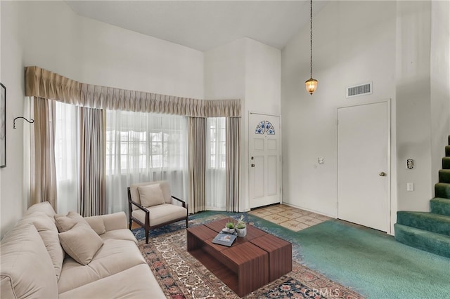 living room featuring a towering ceiling and carpet flooring