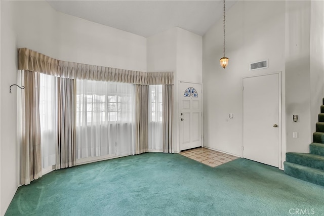 entrance foyer with carpet flooring and high vaulted ceiling